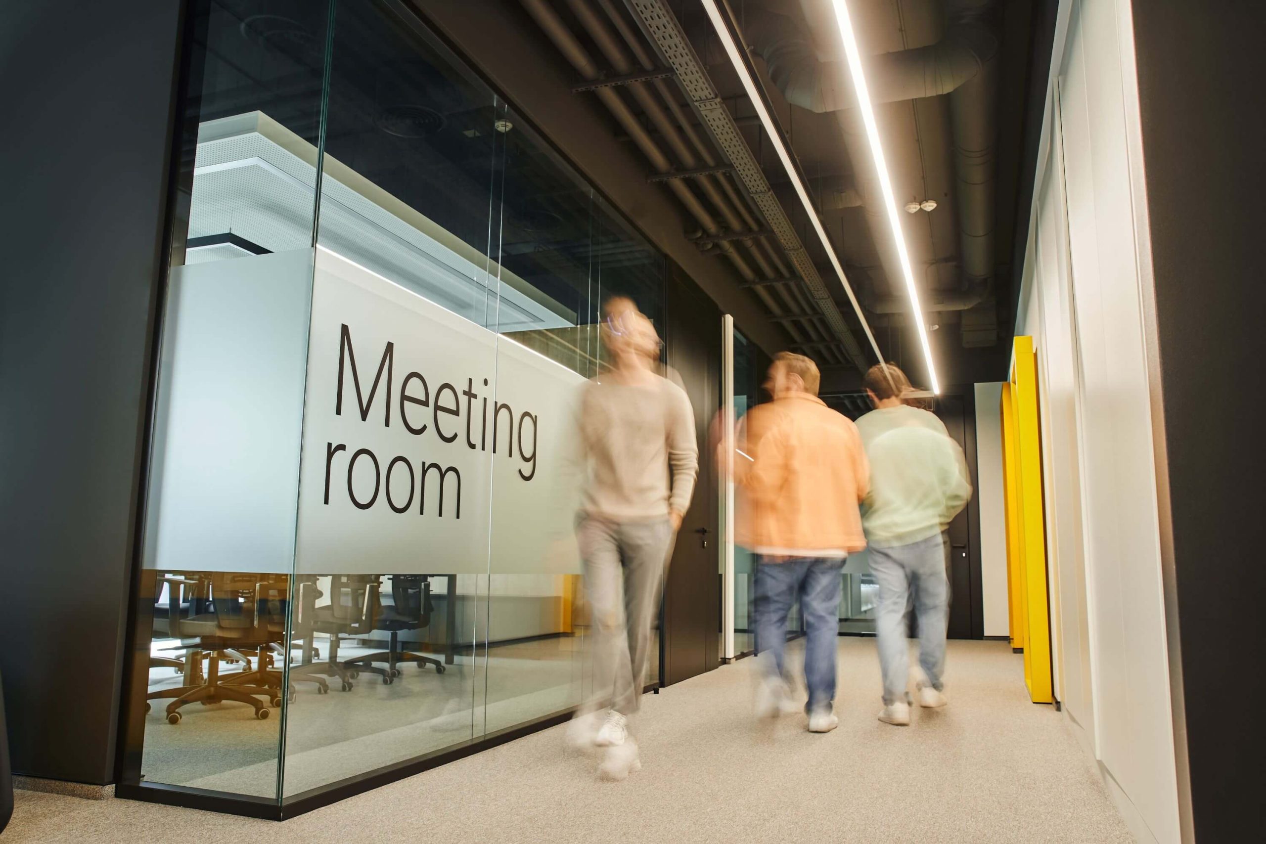 Meeting Room written on the wall with people walking by but camera blurred out with nice black highlights and colorful aurroundings