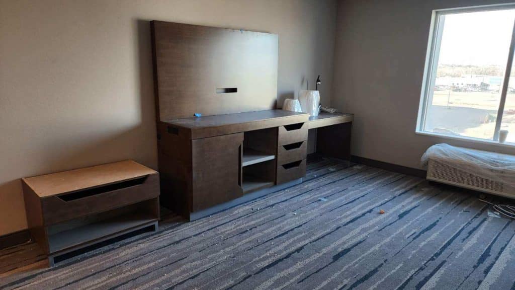  It shows the beginning of an installation of hotel rooms. Blue commercial carpet, window, and TV storage. 